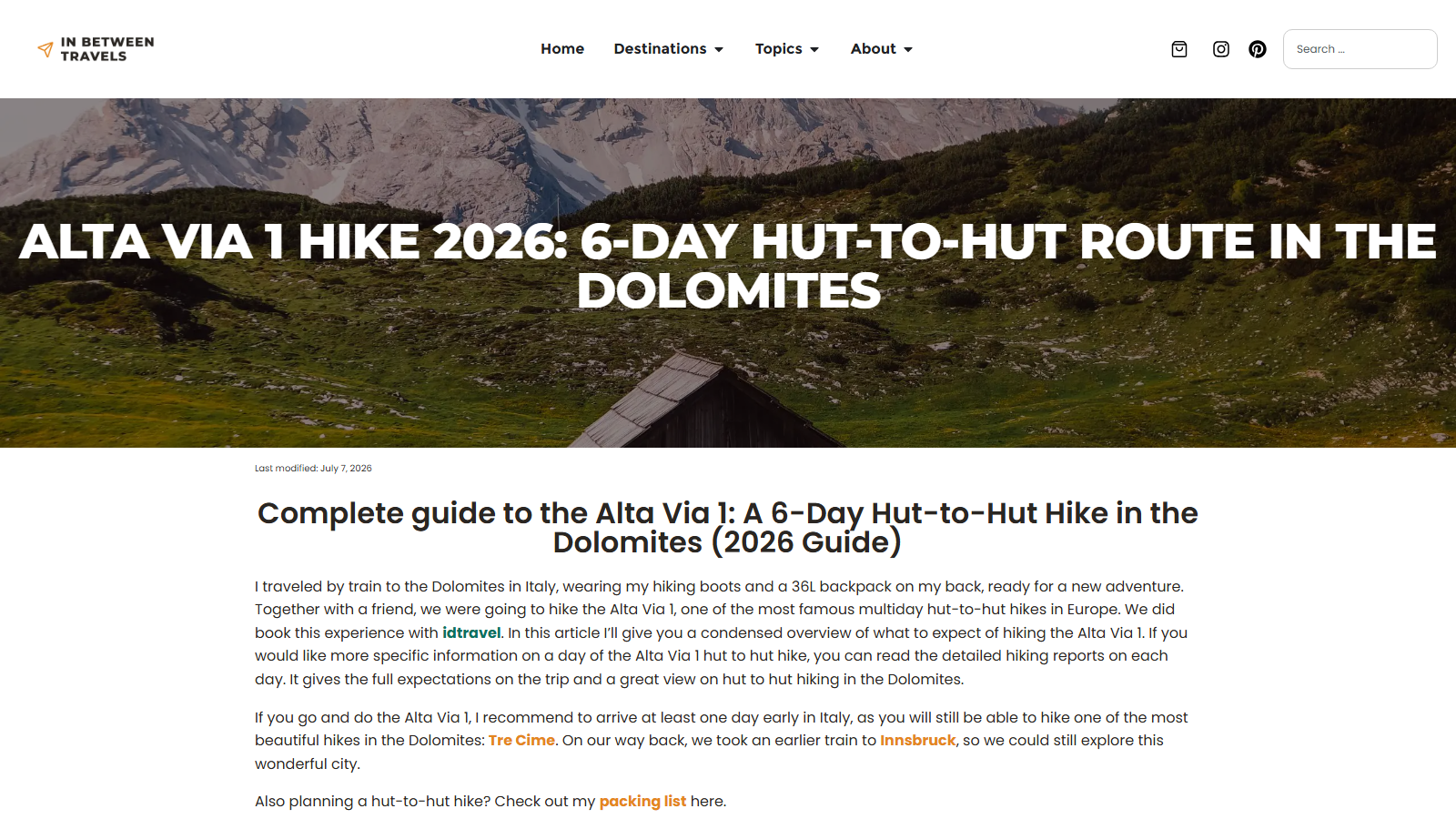 Full-width hero photograph of a dark timber alpine hut on a green slope below a pale limestone massif, overlaid with the headline 'ALTA VIA 1 HIKE 2026: 6-DAY HUT-TO-HUT ROUTE IN THE DOLOMITES', a 'Last modified: July 7, 2026' line, and the opening paragraphs of the guide.