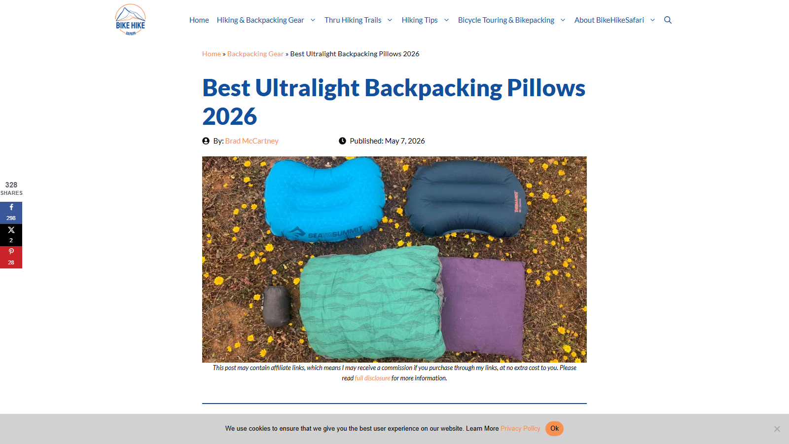 Article headline 'Best Ultralight Backpacking Pillows 2026' by Brad McCartney, published May 7, 2026, above a photo of five camp pillows (two inflatables, a stuff sack and two fabric-covered pillows) laid out on ground scattered with small yellow flowers