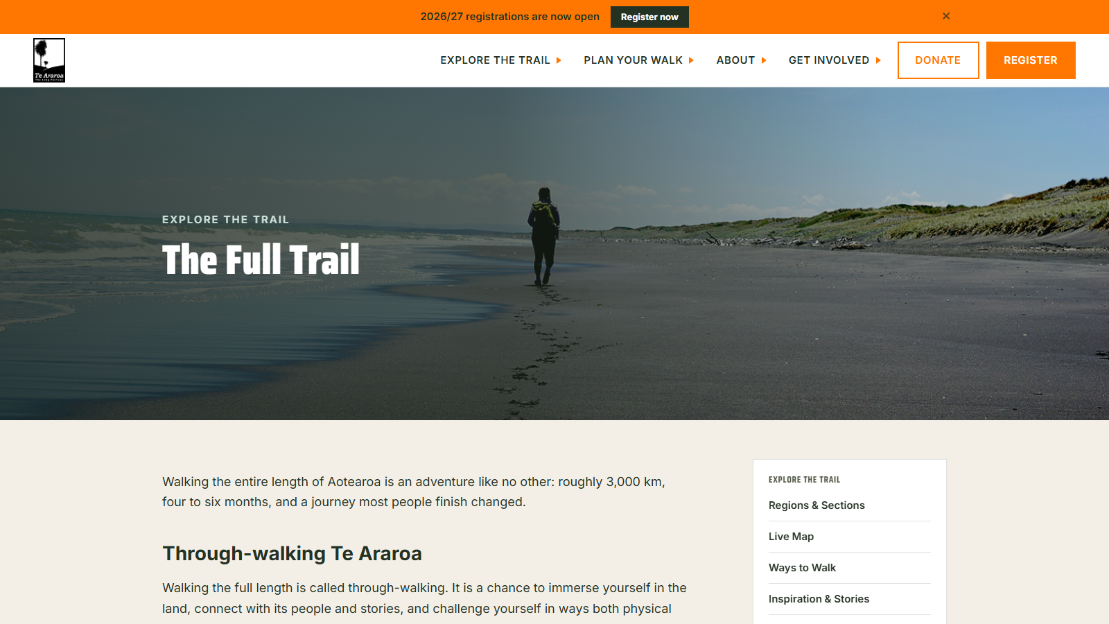 A lone hiker with a yellow-strapped pack walking away down a wide grey-sand beach, footprints trailing behind them toward dune grass and sea, under the heading 'The Full Trail'