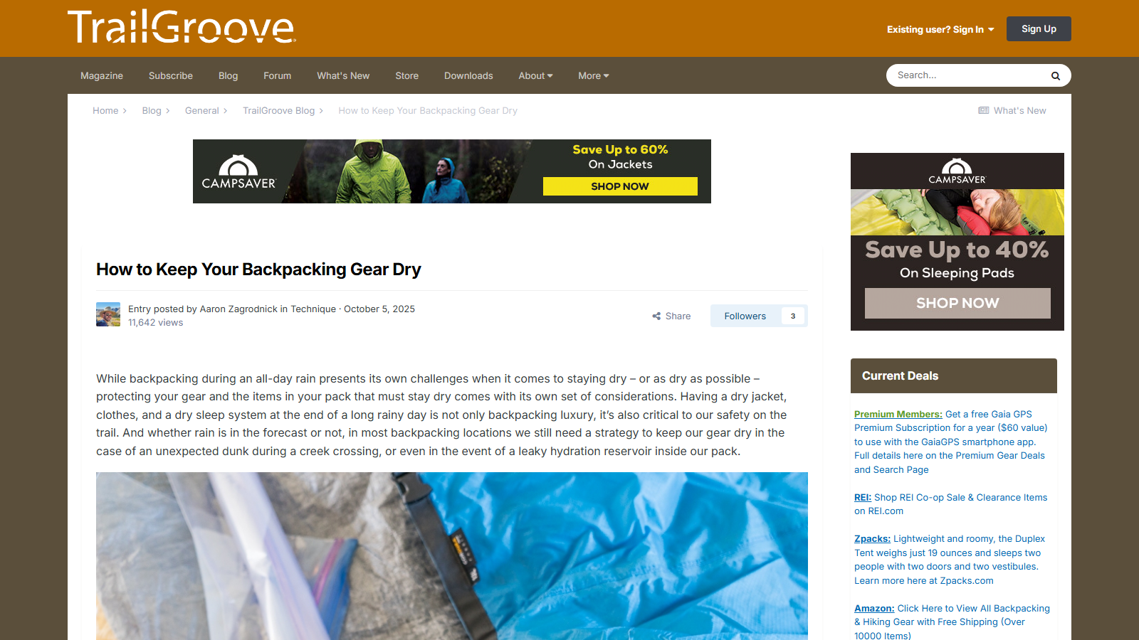 TrailGroove blog post 'How to Keep Your Backpacking Gear Dry' by Aaron Zagrodnick, October 5, 2025, with a CampSaver ad banner above the intro paragraph and a photo of a blue roll-top dry bag beside a clear plastic liner